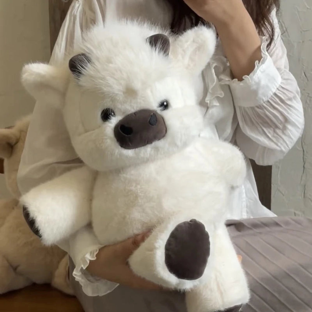 Person holding a white plush toy with black accents