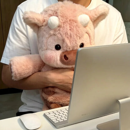 Person holding a pink plush coo bank in front of a computer setup
